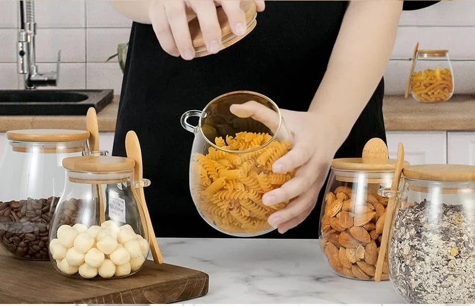 Person arranging glass jars filled with coffee beans, snacks, and pasta, some jars laid on their side