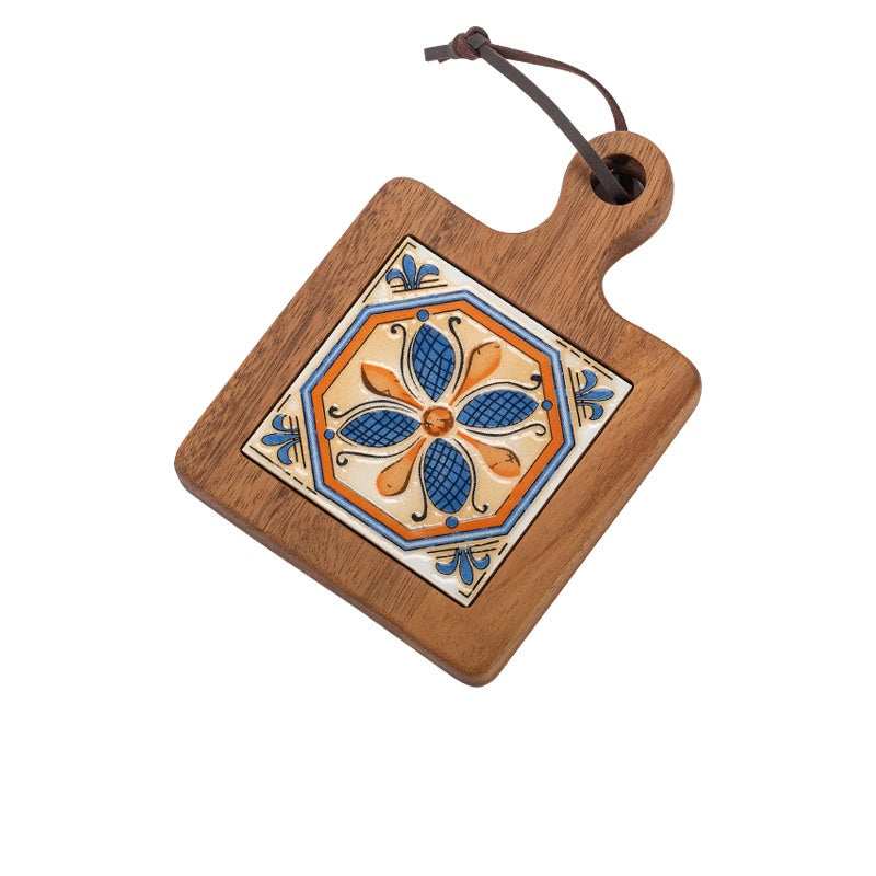 Wooden table mat featuring a blue and orange flower ceramic tile and leather hanging loop