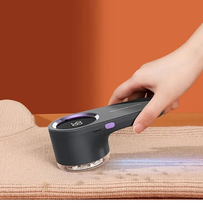 Hand-held digital fabric shaver removing lint from a sweater