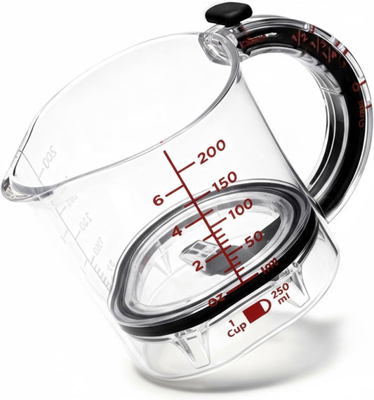 Transparent glass measuring cup with red measurement markings and ergonomic handle