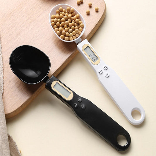 Black and white digital measuring spoons with LCD screens on a light wooden board