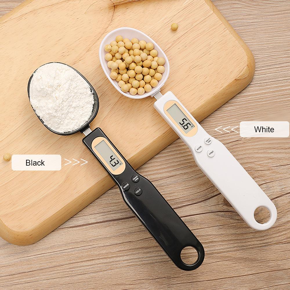 Black and white digital measuring spoons with flour and soybeans on a wooden background