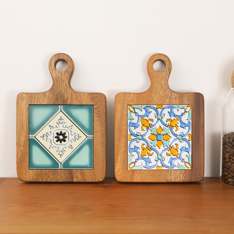 Two wood and ceramic table mats with Mediterranean patterns on a wooden surface
