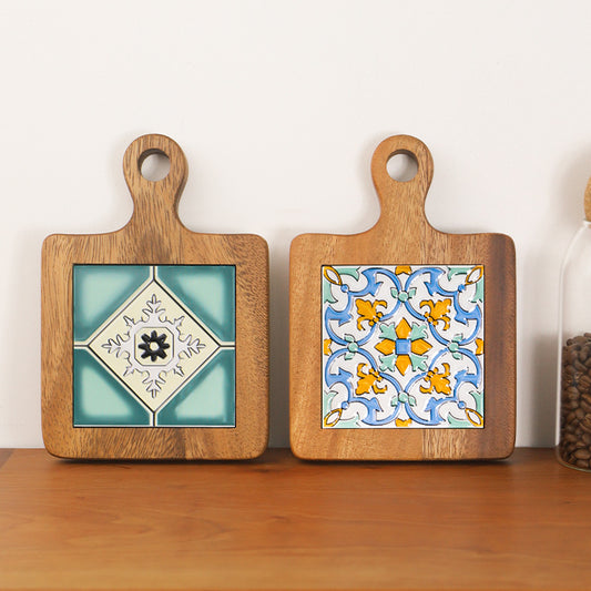 Two wood and ceramic table mats with Mediterranean patterns on a wooden surface