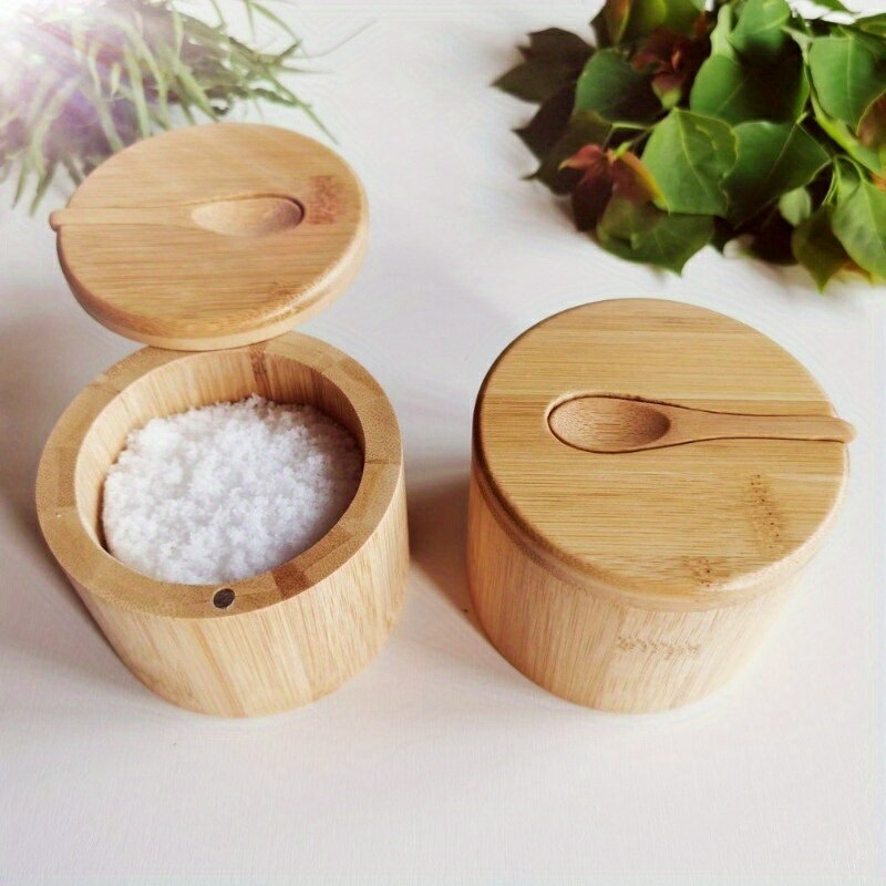 Two bamboo seasoning jars with swivel lids and built-in spoons, one open showing salt inside